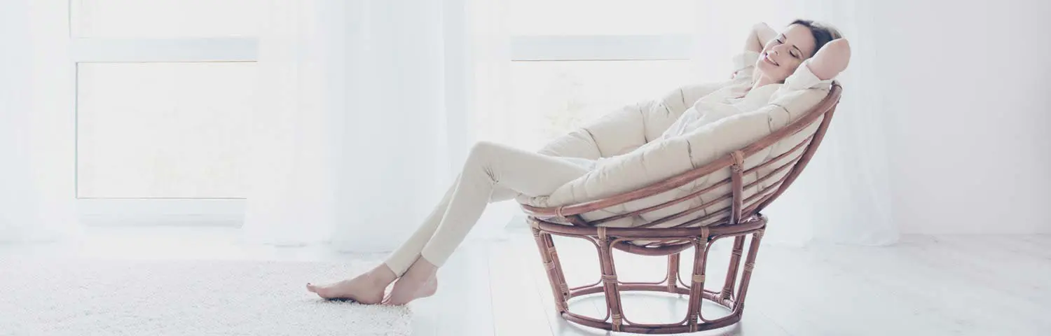 Moving home services - woman relaxing on large wicker chair.